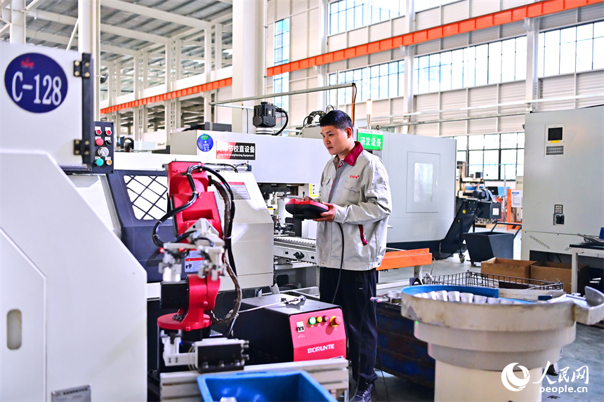 上饒市弋陽縣高新技術產業園區的科技企業車間內，工人在操作智能機械臂加工新能源汽車零部件。人民網 朱海鵬攝
