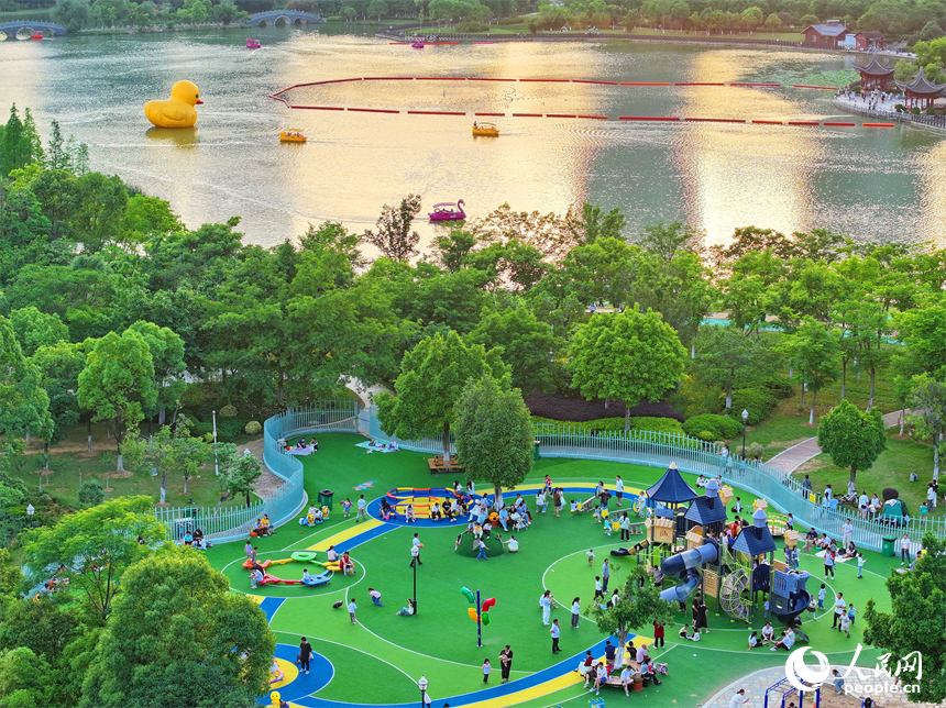 贛州市中心城區的一處公園里，家長帶著孩子在兒童游樂園內游玩，樂享親子時光。人民網 朱海鵬攝