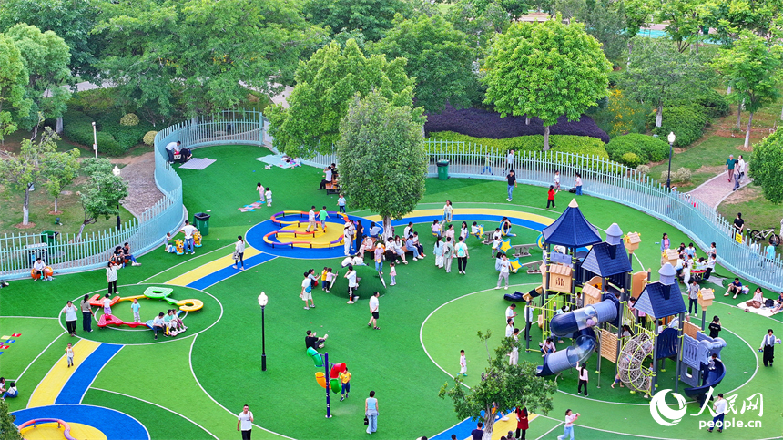 贛州市中心城區的一處公園里，家長帶著孩子在兒童游樂園內游玩，樂享親子時光。人民網 朱海鵬攝