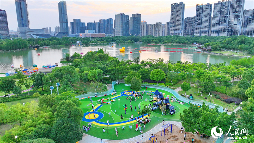 贛州市中心城區的一處公園里，家長帶著孩子在兒童游樂園內游玩，樂享親子時光。人民網 朱海鵬攝