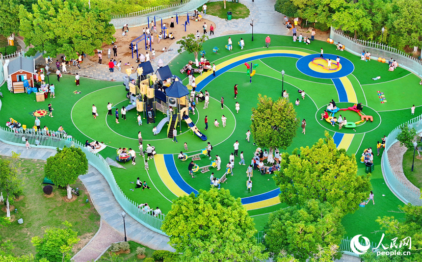 贛州市中心城區的一處公園里，家長帶著孩子在兒童游樂園內游玩，樂享親子時光。人民網 朱海鵬攝