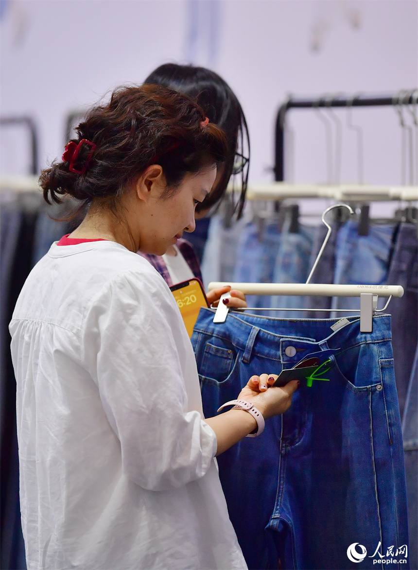 2025中國(南昌)國際服裝服飾博覽會在紅谷灘區舉行。圖為采購商正在挑選服飾產品。人民網記者 時雨攝