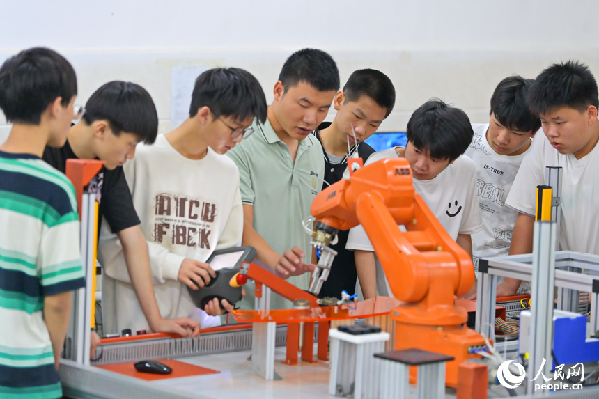 瑞金市瑞金中等專業學校工業機器人實訓基地，老師在指導學生在操作智能機械臂。人民網 朱海鵬攝