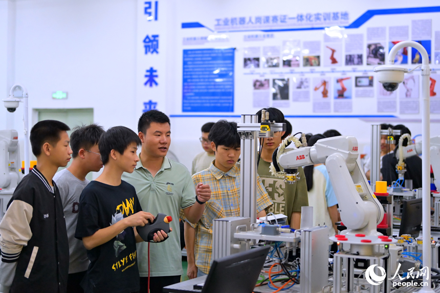 瑞金市瑞金中等專業學校工業機器人實訓基地，老師在指導學生在操作智能機械臂。人民網 朱海鵬攝