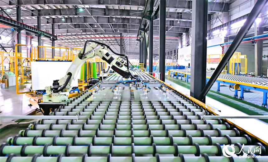 贛州市定南縣的一家新材料企業生產車間的智能機械臂有序運轉，工人在自動化產線上加工光伏玻璃。人民網 朱海鵬攝