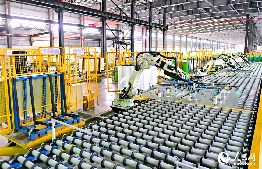贛州市定南縣的一家新材料企業生產車間的智能機械臂有序運轉，工人在自動化產線上加工光伏玻璃。人民網 朱海鵬攝