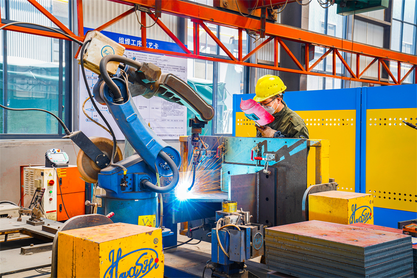 工人正在觀察自動焊接機器人作業。郭昊攝