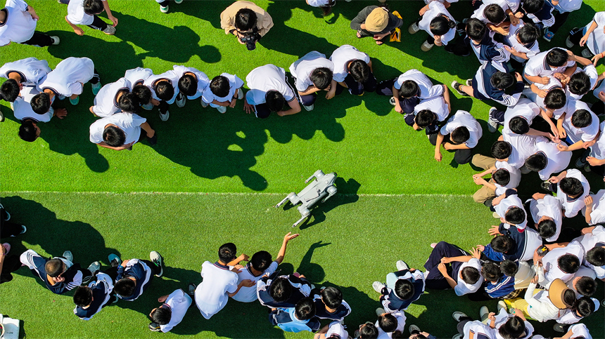 大課間活動時，學生們正在與機器狗進行“人機互動”。郭昊攝