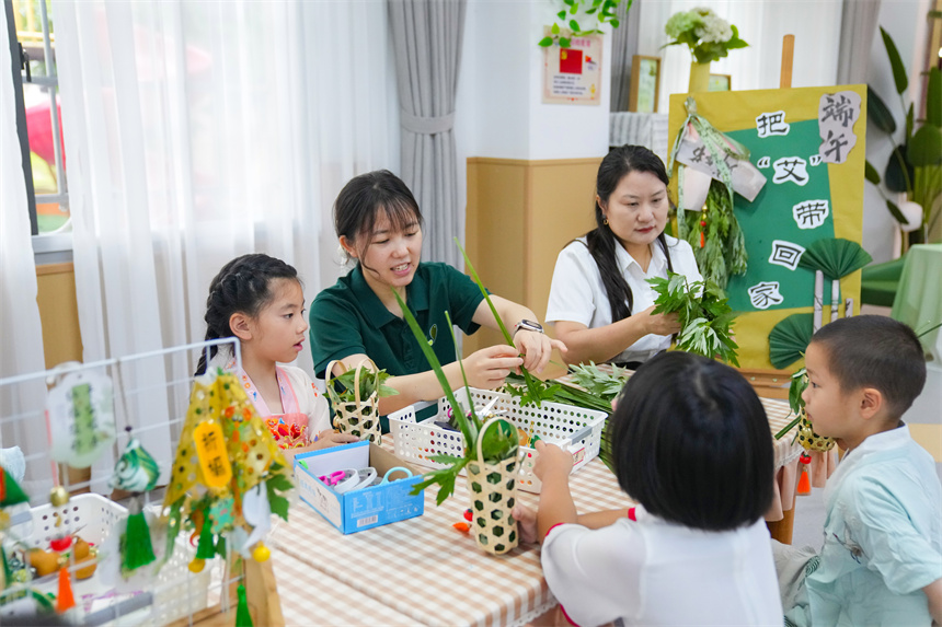 江西省撫州市臨川區保育院里，老師指導孩子們插艾籃。 郭昊攝