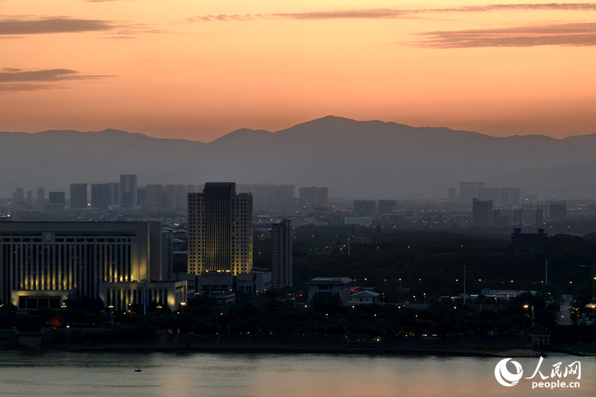 傍晚時分，染紅的天際映襯著梅嶺山脈，與城市初上的華燈相互輝映。人民網記者 時雨攝