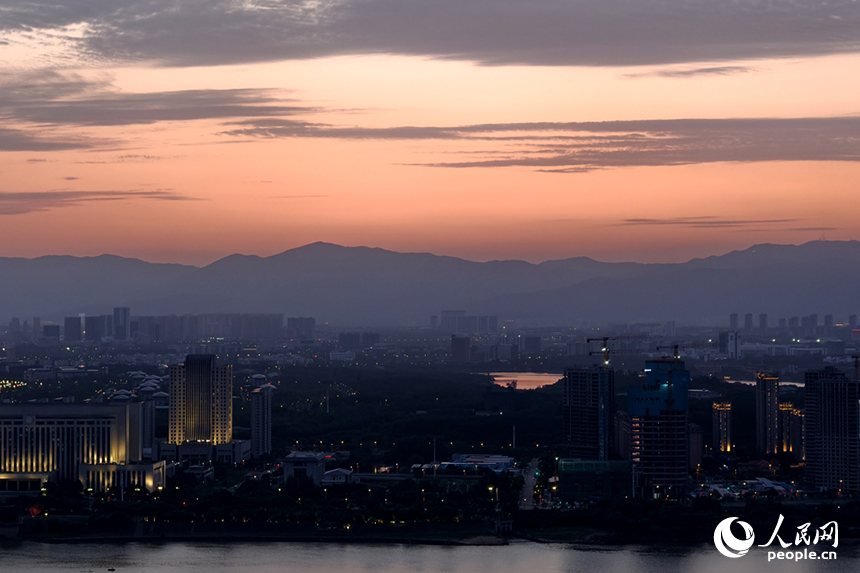 傍晚時分，染紅的天際映襯著梅嶺山脈，與城市初上的華燈相互輝映。人民網記者 時雨攝