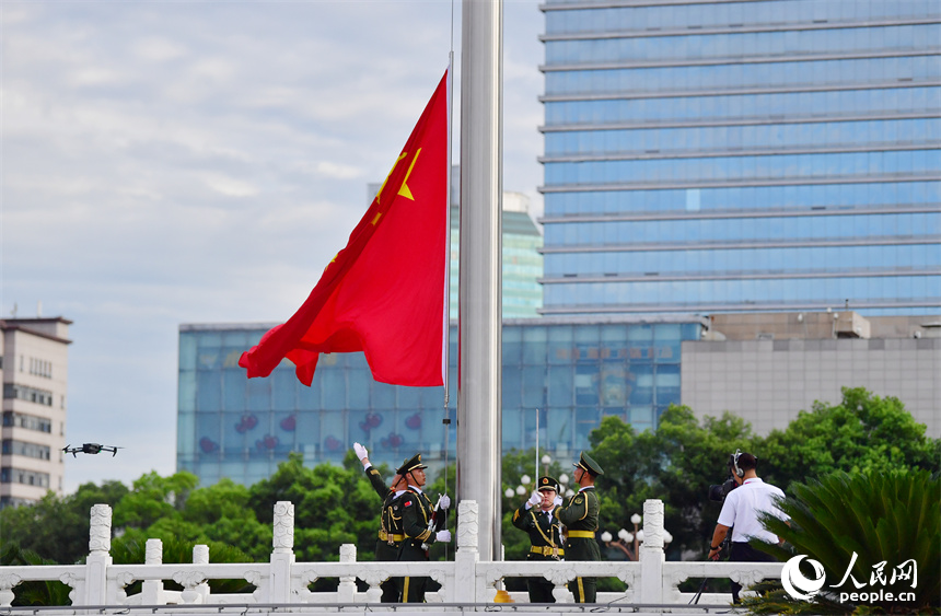 升旗手迎風振臂，將國旗拋向天空。人民網記者 時雨攝