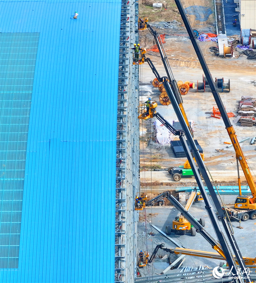 建設者們冒著高溫在高空進行貨棚擋板安裝作業。人民網 朱海鵬攝