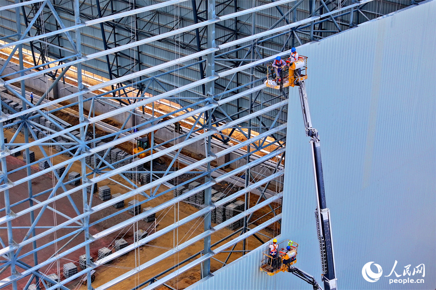 建設者們冒著高溫在高空進行貨棚擋板安裝作業。人民網 朱海鵬攝