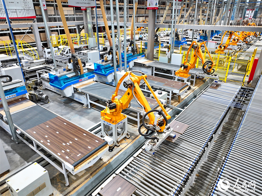 贛州市南康區國際家居總部經濟區的一家企業全屋整裝智能制造車間內，工人在操作智能機器人手臂裁切家具板材。人民網 朱海鵬攝