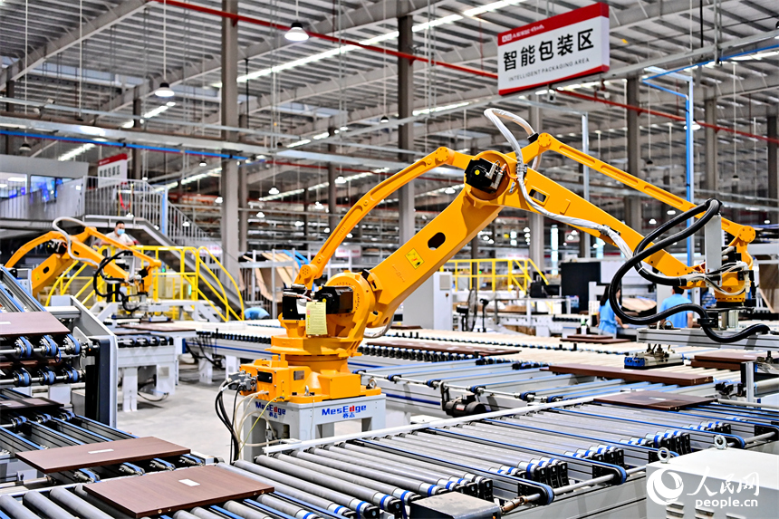 贛州市南康區國際家居總部經濟區的一家企業全屋整裝智能制造車間內，工人在操作智能機器人手臂裁切家具板材。人民網 朱海鵬攝