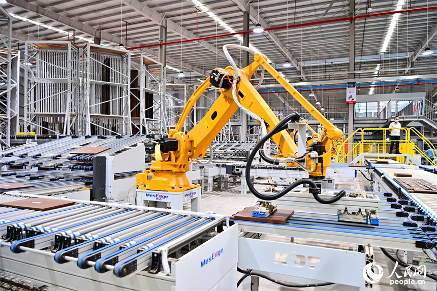 贛州市南康區國際家居總部經濟區的一家企業全屋整裝智能制造車間內，工人在操作智能機器人手臂裁切家具板材。人民網 朱海鵬攝