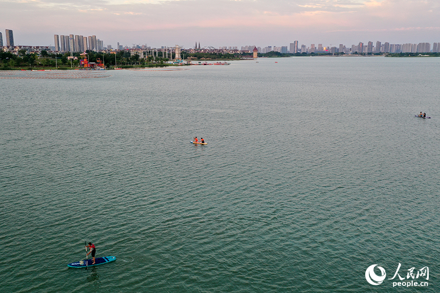 夕陽下，紅谷灘區九龍湖泛著金色波光，槳板愛好者們正在湖面揮槳劃行。人民網記者 時雨攝