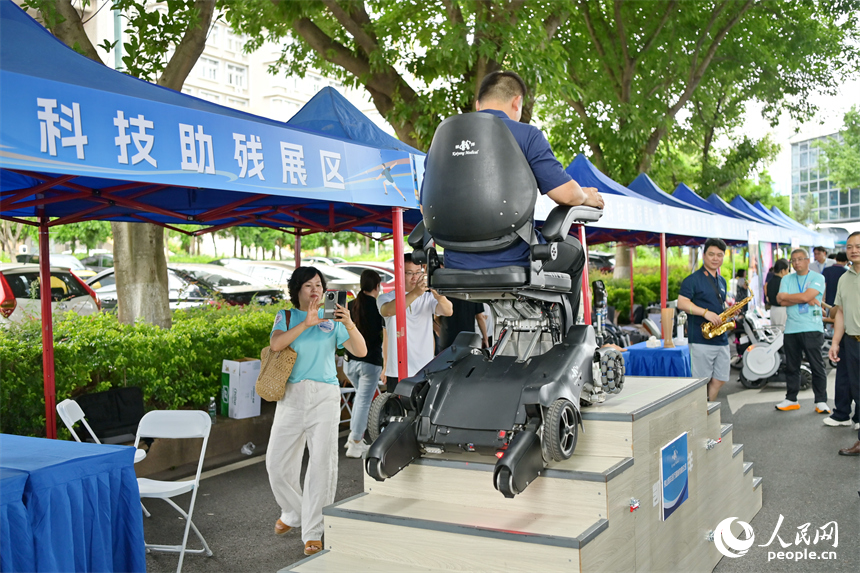 參觀者在科技助殘展區咨詢試用無障礙爬樓機器人產品。人民網 朱海鵬攝