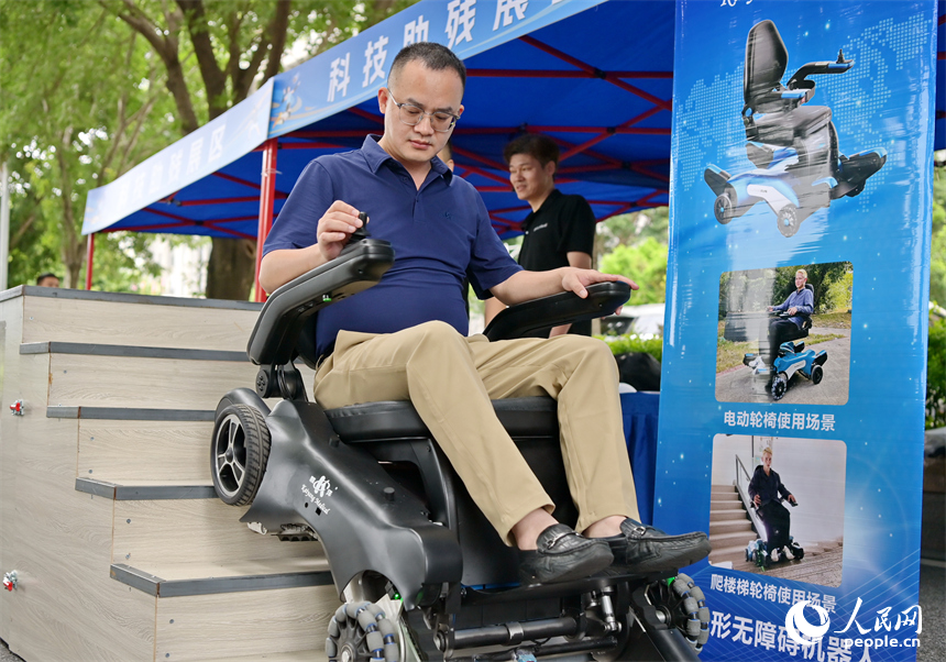 參觀者在科技助殘展區咨詢試用無障礙爬樓機器人產品。人民網 朱海鵬攝
