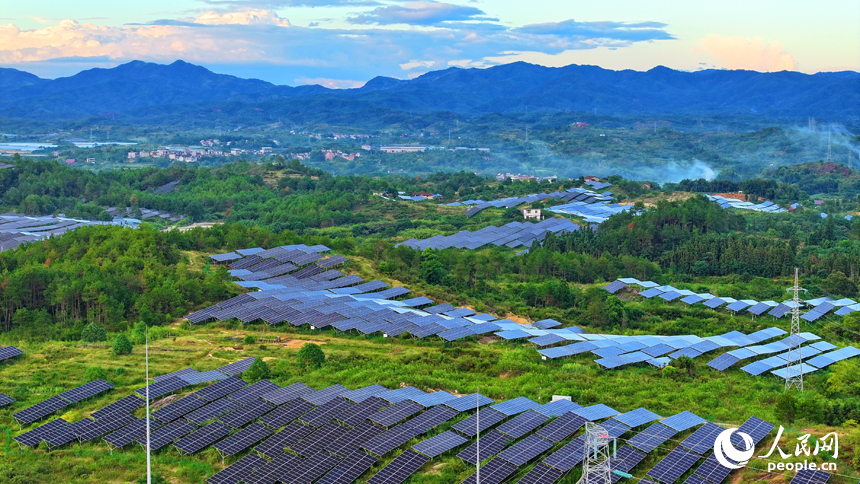 撫州市南豐縣萊溪鄉西山村“農光互補”光伏發電站，荒山坡上安裝的光伏板熠熠生輝，與綠樹青山相映相襯。人民網 朱海鵬攝