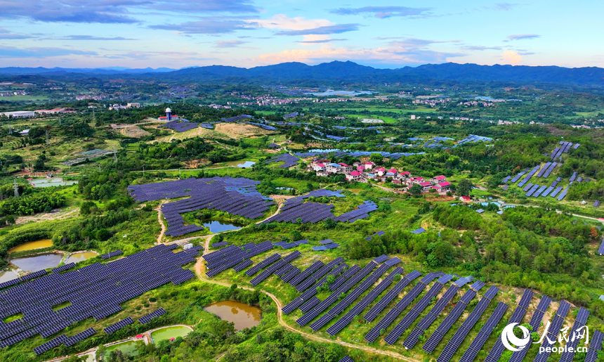 撫州市南豐縣萊溪鄉西山村“農光互補”光伏發電站，荒山坡上安裝的光伏板熠熠生輝，與綠樹青山相映相襯。人民網 朱海鵬攝