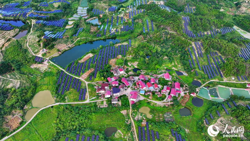 撫州市南豐縣萊溪鄉西山村“農光互補”光伏發電站，荒山坡上安裝的光伏板熠熠生輝，與綠樹青山相映相襯。人民網 朱海鵬攝