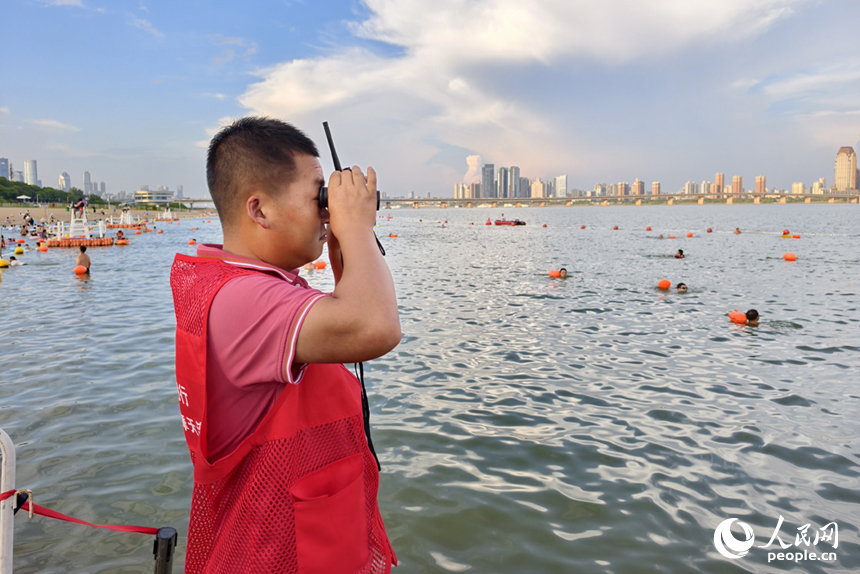 在岸邊的安全員通過望遠鏡觀察水中情況。人民網記者 時雨攝