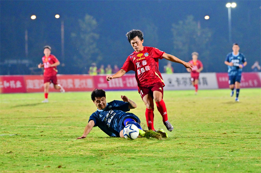 身穿紅色球員的宜春隊球員和身穿藍色球衣的景德鎮球員在綠茵場上激烈拼搶。劉勇攝