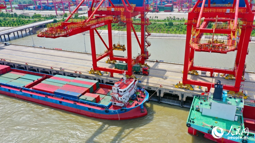 九江市彭澤縣的九江紅光國際港，碼頭貨輪穿梭，工人堅守崗位一線，集裝箱裝卸作業有序進行。人民網 朱海鵬攝