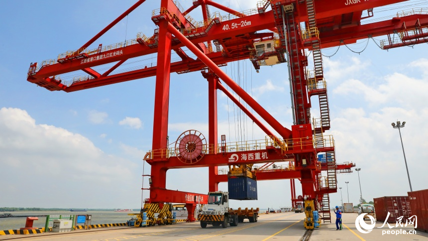 九江市彭澤縣的九江紅光國際港，碼頭貨輪穿梭，工人堅守崗位一線，集裝箱裝卸作業有序進行。人民網 朱海鵬攝