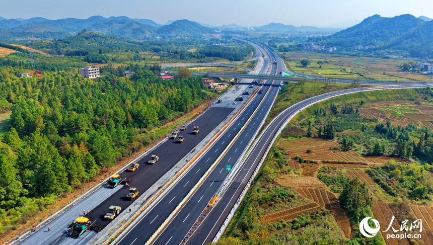 滬昆高速昌傅至金魚石（贛湘界）段改擴建項目施工現場機械轟鳴，工人在攤鋪路面瀝青。人民網記者 朱海鵬攝