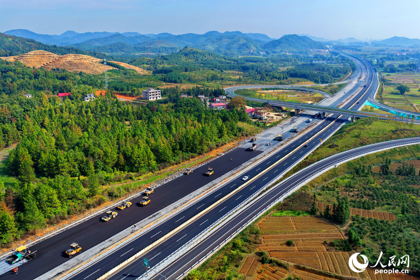 滬昆高速昌傅至金魚石（贛湘界）段改擴建項目施工現場機械轟鳴，工人在攤鋪路面瀝青。人民網記者 朱海鵬攝